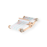 A portable Ashford Knitters Weaving Loom with a smooth lacquer finish, shown in a folded state with multicolored threads woven on it.